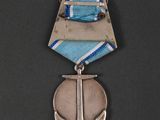 an old silver medal with a blue ribbon and an anchor on it