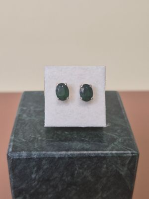 a close up of a pair of green stone earrings on a marble block