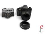 two cameras sitting next to each other on a white surface