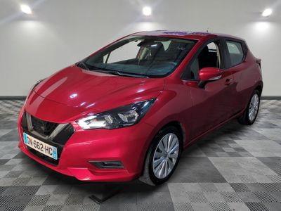 une Nissan Versa rouge garée sur un sol à damier dans un garage