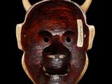 a close up of a wooden mask with horns on a black background