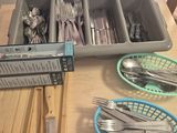 un plateau d'argenterie posé sur une table, avec à côté un panier contenant des fourchettes et des cuillères