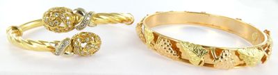 two gold rings and a bracelet are sitting on a white surface