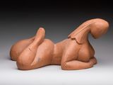 une photo d'une sculpture en argile représentant un chien couché sur le flanc