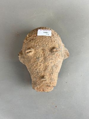 une image représentant une tête en pierre sur laquelle est accrochée une étiquette