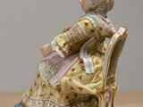a figurine of a woman sitting on a chair