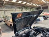 cars are parked in a garage with an open hood