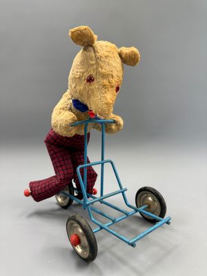 un ours en peluche assis sur un petit chariot