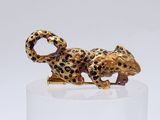 a gold and leopard figurine sitting on a clear pedestal