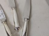 three silver plated knives and a knife holder on a table