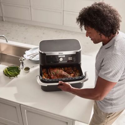 a man standing in front of an air fryer with food in it