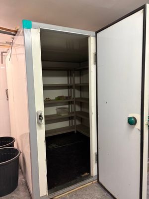 une grande porte ouverte donnant sur une pièce où se trouve une poubelle