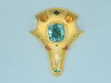 a gold brooch with a green stone in it