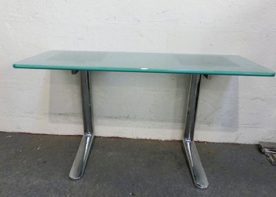 une table en verre avec des pieds en métal et un plateau en verre