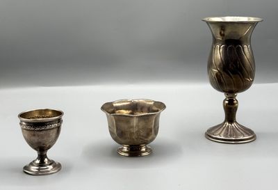 deux vases en argent et une coupe en argent posés sur un fond blanc