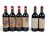 six bottles of wine are lined up on a white surface