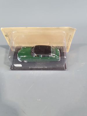 a green toy car in a plastic box on a table