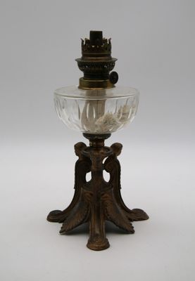 une lampe à huile ancienne en laiton et en verre, ornée d'un oiseau sur le socle