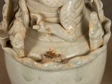 a white vase with a frog on it on a table