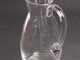 a clear glass pitcher with a handle on a table