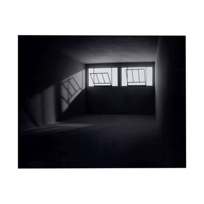 une photo en noir et blanc d'une pièce sombre avec des fenêtres