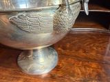 a silver bowl with a bird on it on a wooden table