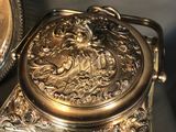 a silver plate with a silver lid and a silver plate with a picture of a lion on it