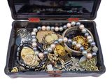 a black case filled with assorted jewelry on a white surface