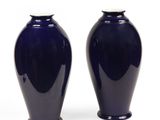 une paire de vases bleu foncé posés sur une surface blanche