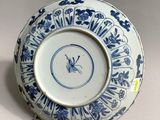 a blue and white plate on a stand with a clock on it