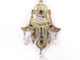 an image of a gold pendant with pearls hanging from it ' s sides