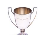 coupe de trophée plaquée argent posée sur un socle, sur fond blanc