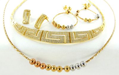 Ensemble composé d'un collier, d'un bracelet et d'une bague en or et en argent, posé sur un fond blanc