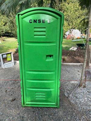 des toilettes portables vertes posées au milieu d'un terrain en gravier
