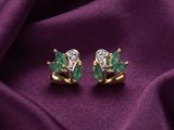 a pair of emerald and diamond earrings on a purple cloth