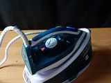 un fer à repasser à vapeur bleu et blanc posé sur une table en bois