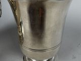 a silver pitcher sitting on a table next to a spoon