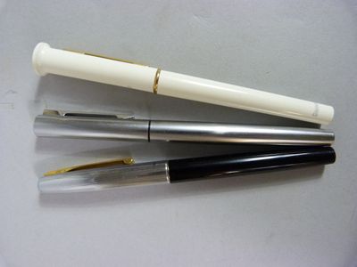 trois stylos sont alignés les uns au-dessus des autres sur une table