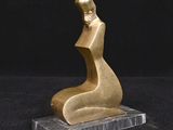 une statue en or représentant une femme assise sur un socle en marbre