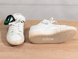 the white sneakers are on a wooden table with a pair of sunglasses