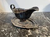 a silver gravy on a plate on a marble table