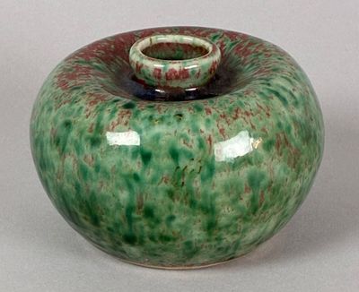 a green and red vase with a white base