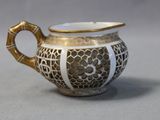 a white and gold cup with a handle on a table