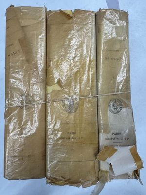 trois vieux livres sont emballés dans du papier kraft sur un fond blanc