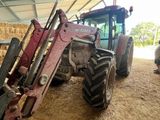 un tracteur garé dans une grange où il y a du foin par terre