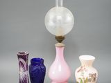 trois vases et une lampe posés sur une table, sur fond gris