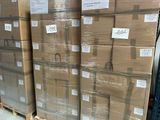 Plusieurs piles de cartons sont empilées sur des palettes dans un entrepôt