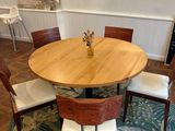 a round table with four chairs and a vase on it