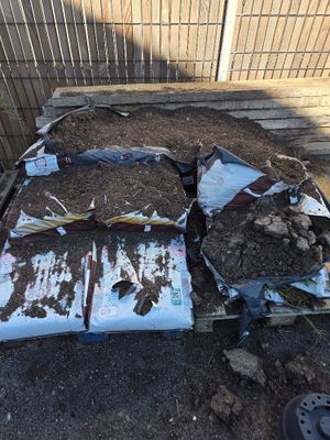 a pile of dirt on the ground next to a fence