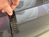 a person that is holding a ruler in front of a car